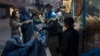 A man distributes bread to burqa-wearing Afghan women outside a bakery in Kabul.