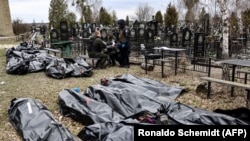 Bodies are lined up for identification by forensic personnel in the cemetery in Bucha, north of Kyiv, on April 6, 2022, after hundreds of civilians were found dead in areas from which Russian troops had withdrawn.