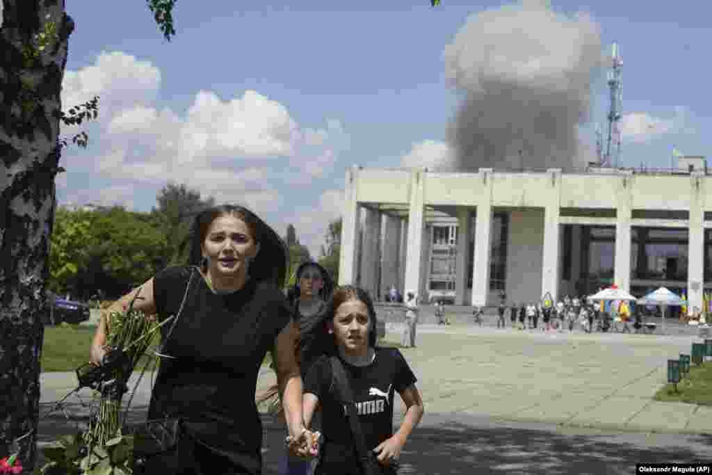 A family runs from an explosion after a Russian missile strike on a residential neighborhood in Pervomayskiy, in Ukraine's northeastern Kharkiv region, on July 4. Ukrainian officials said at least 40 people, including 12 children, were wounded in the attack.