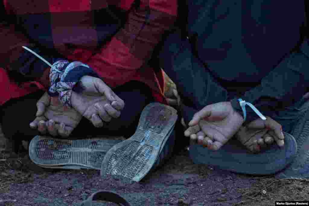 Pritvoreni migranti sjede na koljenima s rukama vezanim lisicama u blizini svog improviziranog kampa blizu granice. "Onda ovi pojedinci ponovo padaju u kandže krijumčara koji ponovo traže plaćanje", rekao je on, dodajući da su različite kriminalne grupe bile uključene u krijumčarenje migranata i međusobno nasilje.