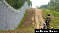 A Latvian border guard patrols along the fence at the border with Belarus near Robeznieki.