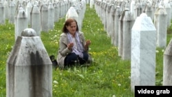 A woman prays amid the gravestones of Srebrenica victims at a memorial cemetery in Potocari. 