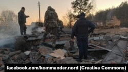 Ukrainian workers inspect the aftermath of Russian shelling in Semenivka in 2023. 
