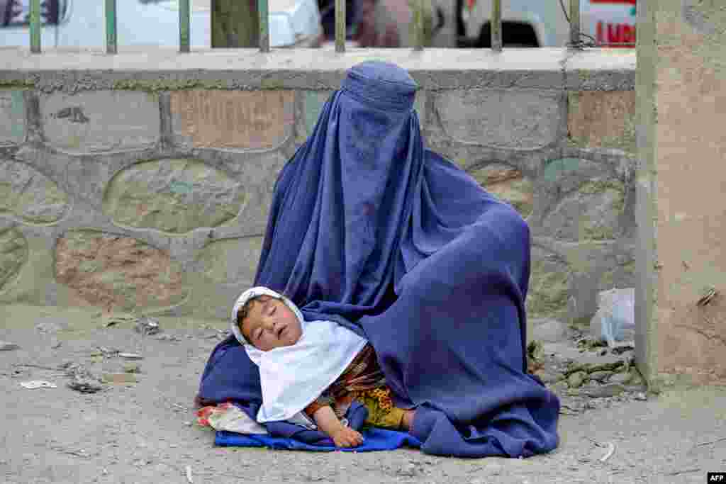 An Afghan woman holding a child seeks alms along a road in the Argo district of Badakhshan Province.
