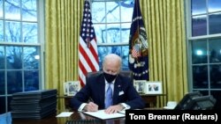 Джо Байден в первый день работы на посту президента США подписывает документы в Белом доме. 20 января 2021 года.