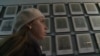 Yevgenia Karatygina in front of portraits of Holocaust victims in a still from the trailer for the documentary "Holocaust -- Wallpaper Paste?"