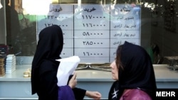 People walk in front of currency exchanges in Tehran.